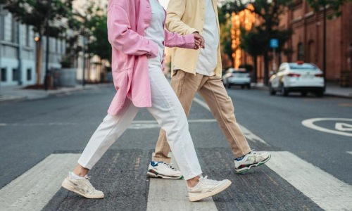 a man and woman walking across a street
