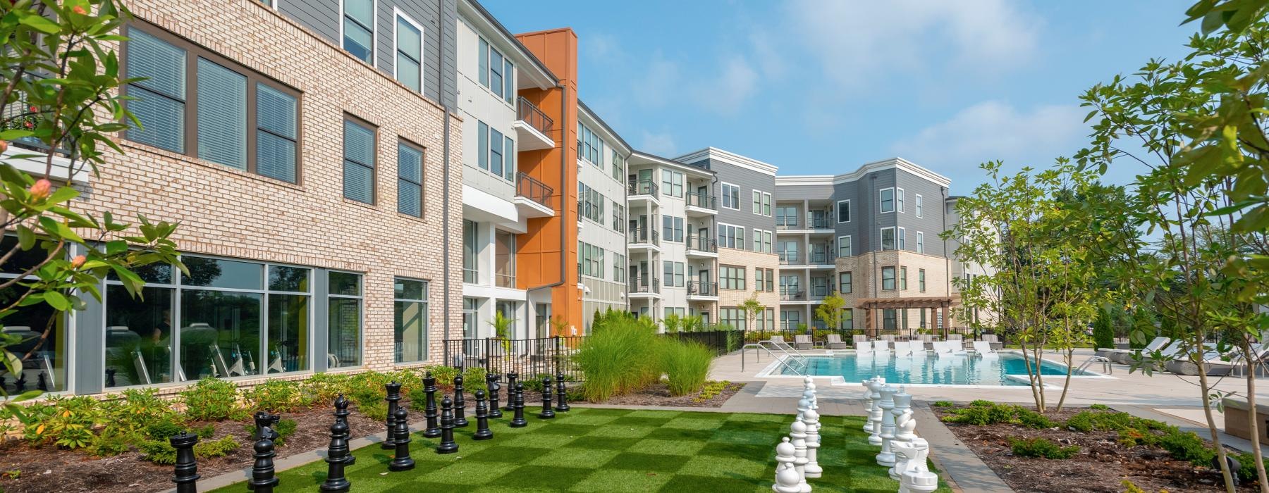 a courtyard with trees and buildings and a large chess board
