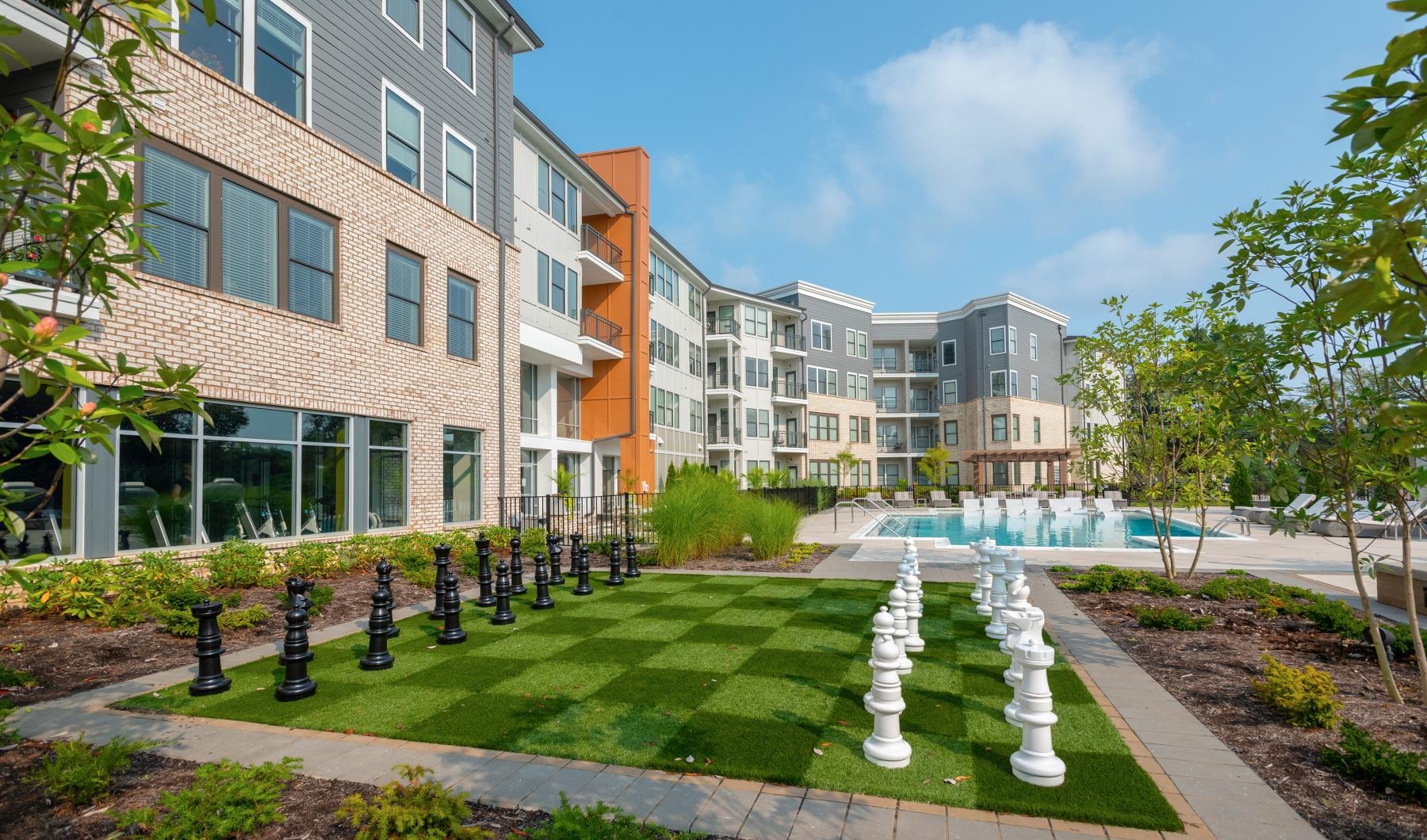 a courtyard with trees and buildings and a large chess board